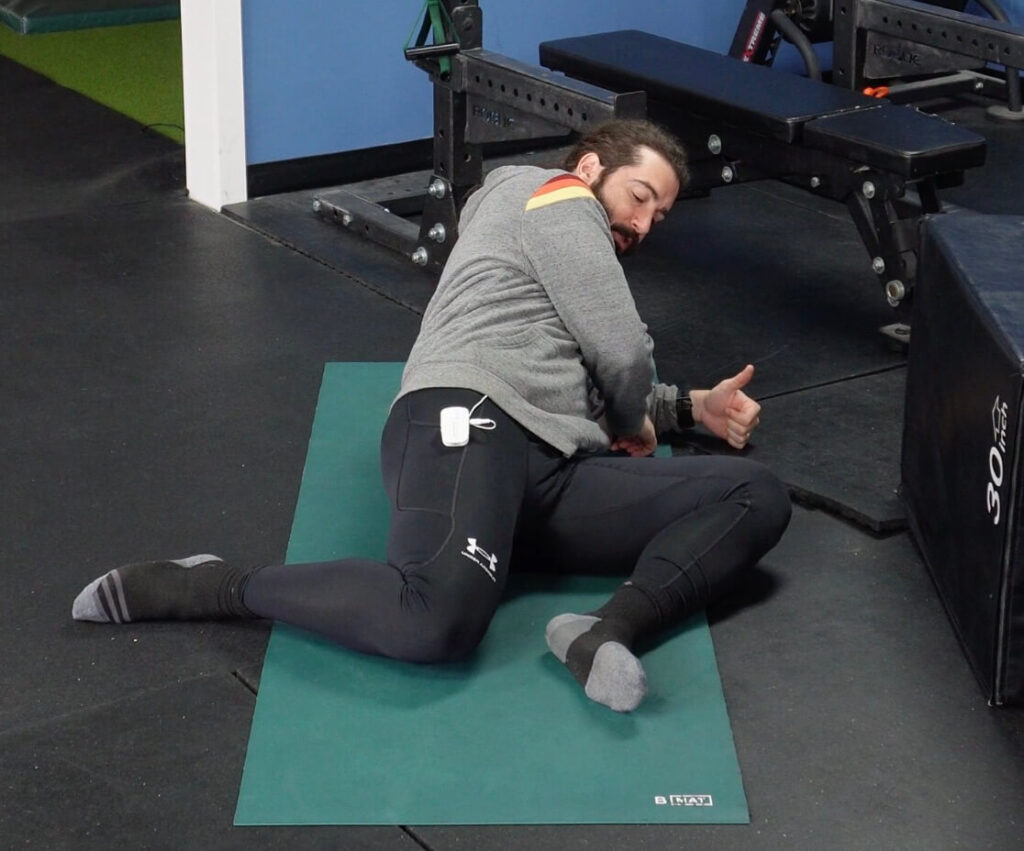 Dr. John on the floor stretching his right hip for his hip mobility routine.